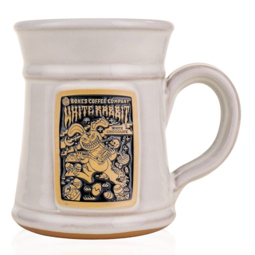 The front of the Bones Coffee Company White Rabbit Handthrown Mug. It has the art for White Rabbit on the golden medallion. The mug is white colored.