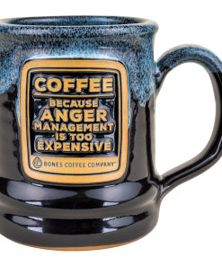 The front of the Bones Coffee Company Anger Management Handthrown Mug. It has the phrase “Coffee, because anger management is too expensive” on the golden medallion. The mug is black colored with a powder blue and white glaze.