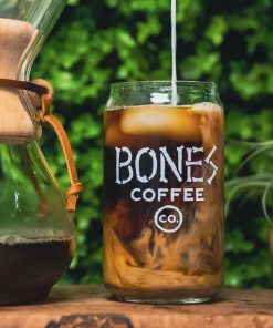 A cold brew glass that has the Bones Coffee Company logo that has the words Bones Coffee Co with the word Bones spelled out with bones. There is coffee inside the cold brew glass.