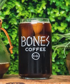 A cold brew glass that has the Bones Coffee Company logo that has the words Bones Coffee Co with the word Bones spelled out with bones. There is coffee inside the cold brew glass.
