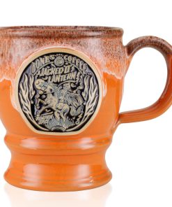 The front of the Bones Coffee Company Jacked O’ Lantern hand thrown mug. The golden medallion has the art of the Jacked O’ Lantern coffee on it. The mug is an orange finish dipped in pumpkin spice glaze.