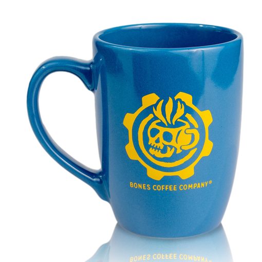The back of the Vault Tech ceramic mug has a yellow Bones Coffee Company logo. The logo is of a skull that looks like a mug with steam coming out of it surrounded by a gear. The ceramic mug is colored blue.