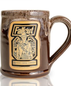 The front of the Bones Coffee Company Ghoul hand thrown mug with the Wasteland Crunch art on the golden medallion. It is inspired by Zenimax and Amazon’s Fallout show. The mug is chocolate colored with a sand white glaze on top.