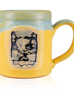The front of the Bones Coffee Company Bikini Bottom Brew hand thrown mug with SpongeBob SquarePants and Gary the snail on the golden medallion. It is inspired by SpongeBob SquarePants. The mug is yellow colored and has a blue and white glaze on top of it.
