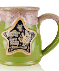 The front of the Bones Coffee Company Goofy Goober Sundae hand thrown mug with Squidward and Plankton on the golden medallion. It is inspired by SpongeBob SquarePants. The mug is moss green colored and has a pink and white glaze on top of it.