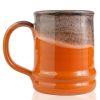 The back of the Pumpkin King hand thrown mug. It is orange colored with a black and white glaze on top.