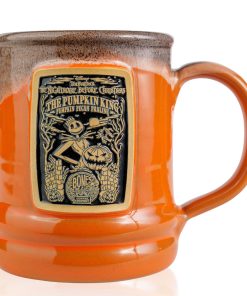The front of the Bones Coffee Company Pumpkin King hand thrown mug with Jack Skellington on the golden medallion. The mug is orange colored with a black and white glaze on top.