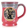 The front of the Bones Coffee Company Soufflé Symphony hand thrown mug with Squidward and Plankton on the golden medallion. It is inspired by SpongeBob SquarePants. The mug is cosmo pink colored and has a teal and white glaze on top of it.