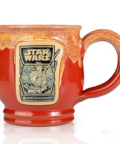 The front of the Bones Coffee Company Twin Sun Tiramisu hand thrown mug with the Twin Sun Tiramisu coffee art on the golden medallion. The mug is paprika colored with a yellow glaze on top. It is inspired by Lucasfilm’s Star Wars.