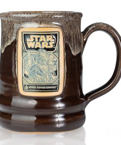 The front of the Bones Coffee Company Wookiee Cookie hand thrown mug with the Wookiee Cookie coffee art on the golden medallion. The mug is chocolate colored with a sand-white glaze on top. It is inspired by Lucasfilm’s Star Wars.